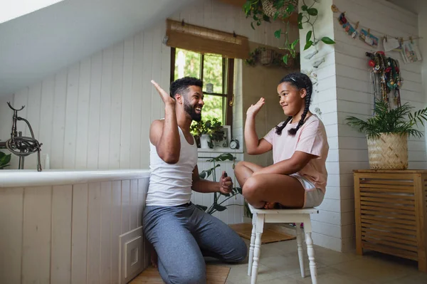 Feliz padre joven con hija pequeña en el interior de casa, dando cinco. — Foto de Stock