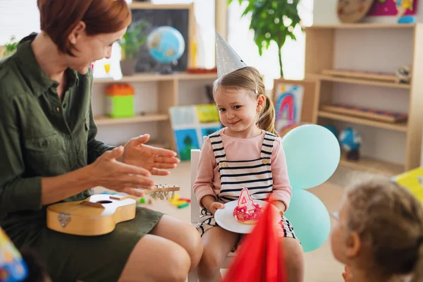 Group of small nursery school children with teacher on floor indoors in classroom, celebration concept. — Stock Photo, Image