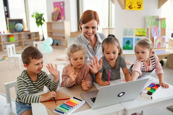 Groep kleine kleuterschoolkinderen met leraar in de klas, met laptop. — Stockfoto