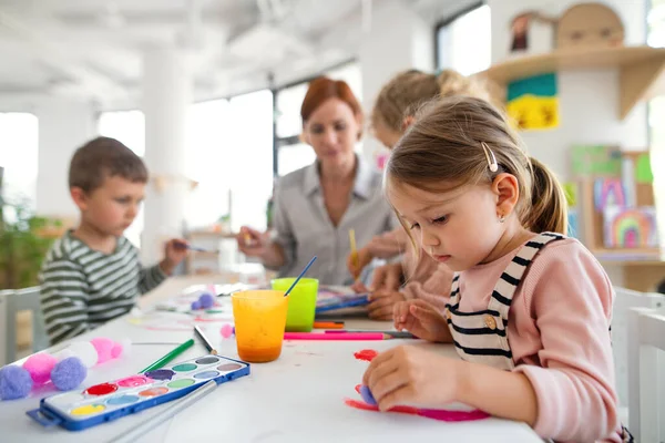 Gruppe kleiner Vorschulkinder mit Lehrerin im Klassenzimmer, Malerei. — Stockfoto