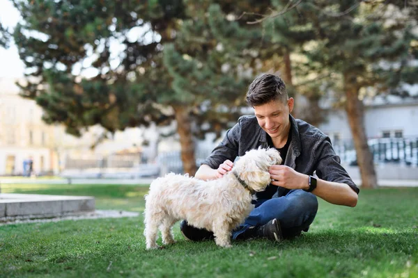 Retrato de jovem com cão ao ar livre no parque da cidade, descansando. — Fotografia de Stock