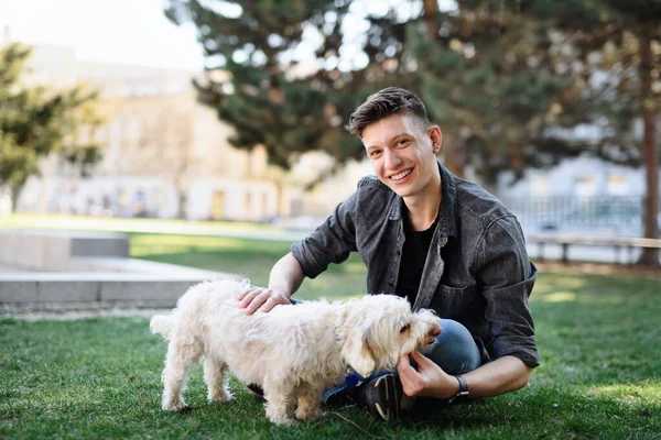 Retrato de jovem com cão ao ar livre no parque da cidade, olhando para a câmera. — Fotografia de Stock