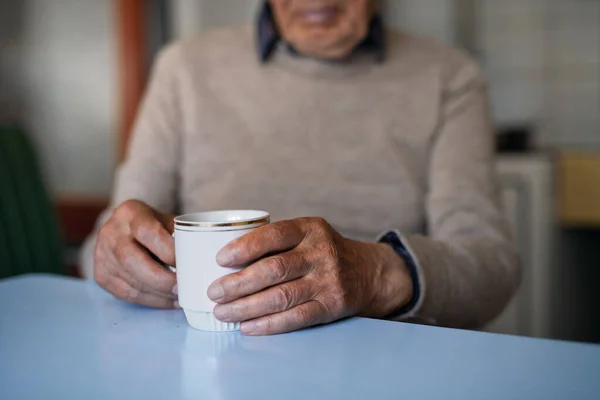 Unerkennbarer älterer Mann mit einer Tasse Tee sitzt zu Hause und ruht sich aus. — Stockfoto