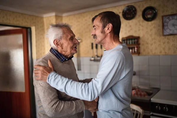 Retrato del hombre con padre anciano en casa, estrechando las manos. —  Fotos de Stock