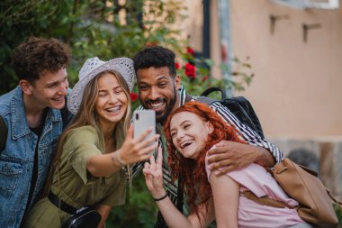 Şehir dışına geziye çıkmış bir grup gencin portresi, akıllı telefondan selfie çekiyor..