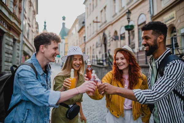 Vista frontal do grupo de jovens felizes com bebidas ao ar livre na rua em viagem à cidade, rindo. — Fotografia de Stock
