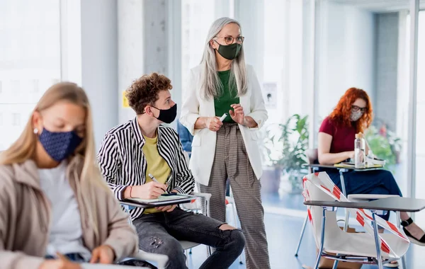 Retrato de estudante universitário com professor em sala de aula dentro de casa, coronavírus e de volta ao conceito normal. — Fotografia de Stock