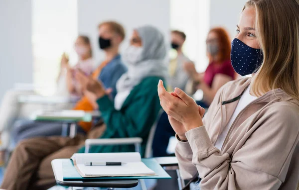 Estudiantes universitarios aplaudiendo en el aula en interiores, coronavirus y volviendo al concepto normal. — Foto de Stock