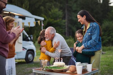 Doğumgününü dışarıda, kamp alanında, karavan tatilinde kutlayan çok nesilli aile..