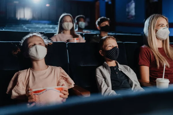 Мама з щасливими маленькими дітьми дивиться фільм у кіно, концепція коронавірусу . — стокове фото