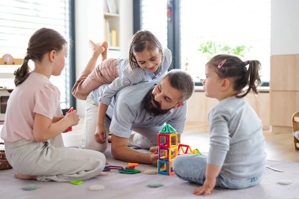 Padre con tre figlie in casa a giocare sul pavimento. — Foto Stock