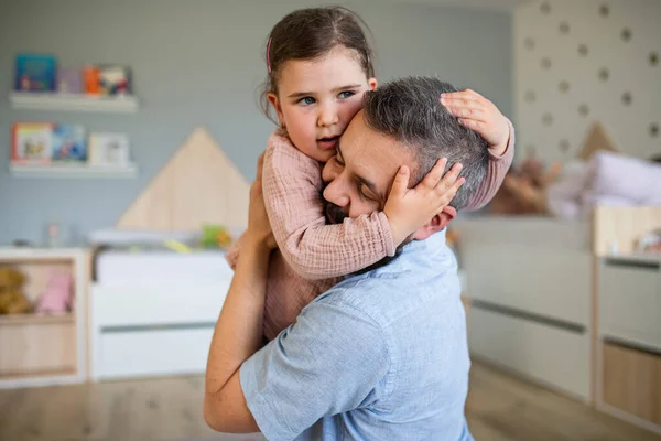 Gelukkig vader met dochter binnen thuis, knuffelen. — Stockfoto