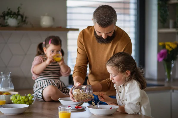 Father with three daughters indoors at home, eating breakfast in kitchen. — Stock Photo, Image