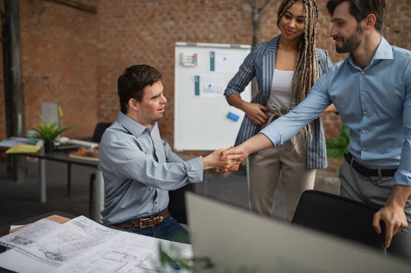 Down syndrome man shaking hands with businesspeople in office, social inclusion and cooperation concept. — Stock Photo, Image