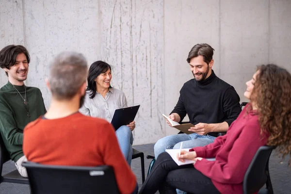 Hommes et femmes heureux assis en cercle pendant la thérapie de groupe, lire et parler. — Photo