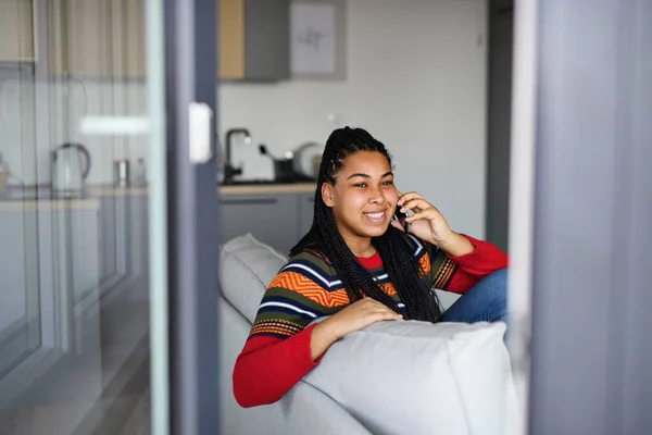 Feliz estudiante adolescente en el sofá en el interior de casa, utilizando el teléfono inteligente. —  Fotos de Stock