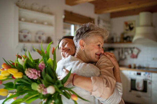 Glad äldre mor kramar vuxen dotter inomhus, mödrar dag eller födelsedag fest. — Stockfoto