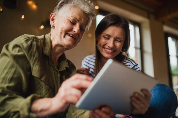 Porträt einer glücklichen Seniorin mit erwachsener Tochter zu Hause mit Tablet. — Stockfoto