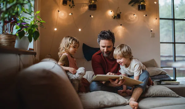 Padre maturo con due bambini piccoli che riposano in casa, guardando l'album fotografico. — Foto Stock