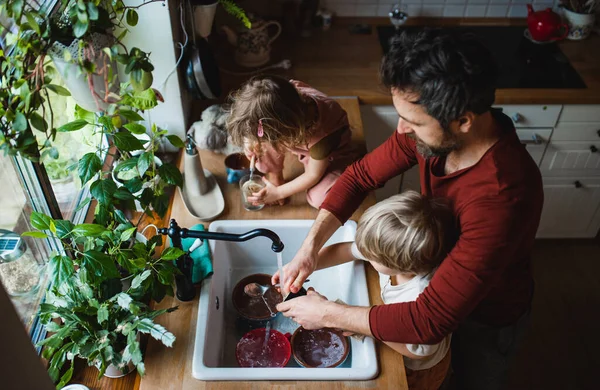 Вид сверху на отца с двумя маленькими детьми, моющих посуду дома, концепция ежедневной рутины. — стоковое фото