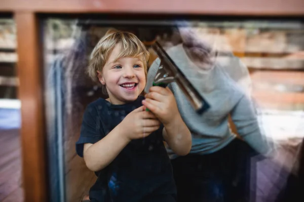 Evde pencereleri temizleyen tanınmayan bir babası olan mutlu çocuk, günlük ev işleri konsepti.. — Stok fotoğraf