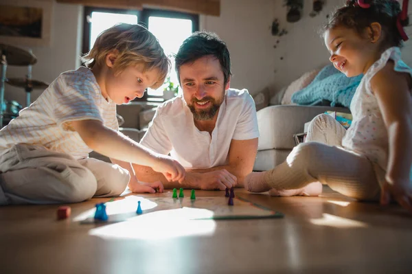 Maduro padre con dos niños pequeños descansando en casa, jugando juegos de mesa. — Foto de Stock