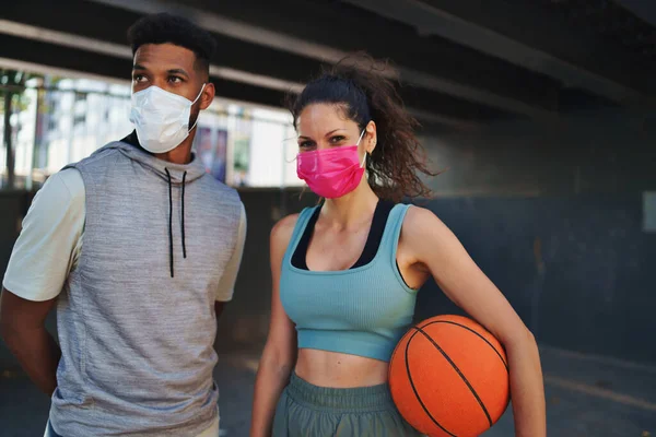 Homem e mulher amigos com basquete fazendo exercício ao ar livre na cidade, olhando para a câmera. Conceito de coronavírus. — Fotografia de Stock