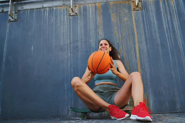 도시 밖에서 농구공을 하고 앉고 쉬고 있는 중년 여자. — 스톡 사진