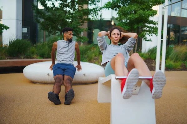 Homem e mulher casal amigos fazendo exercício ao ar livre no parque de treino da cidade. — Fotografia de Stock