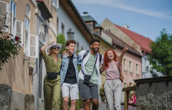 Vista frontal do grupo de jovens felizes ao ar livre em viagem na cidade, andando de braço dado. — Fotografia de Stock