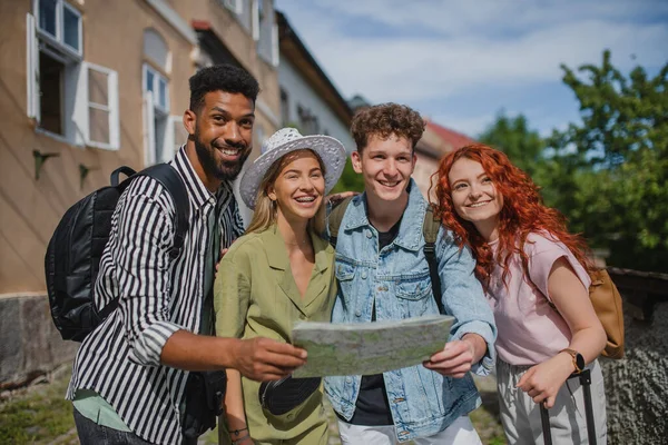 Porträtt av grupp ungdomar utomhus på resa i stan, med hjälp av karta. — Stockfoto