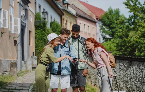 Group of young people outdoors on trip in town, using online map on smartphone. — Stock Photo, Image