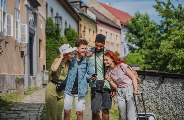 Group of young people outdoors on trip in town, using online map on smartphone. — Stock Photo, Image