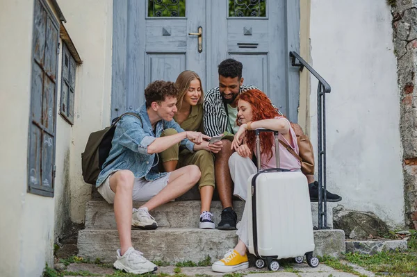 Group of young people outdoors on trip in town, using online map on smartphone. — Stock Photo, Image