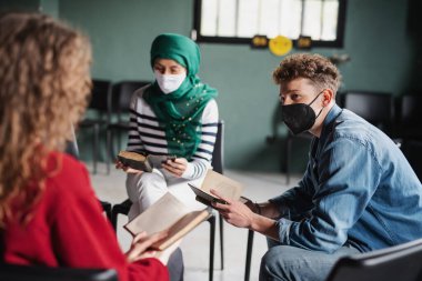 Erkekler ve kadınlar grup terapisi sırasında çember halinde oturup kitap okuyup konuşuyorlar. Coronavirus konsepti.