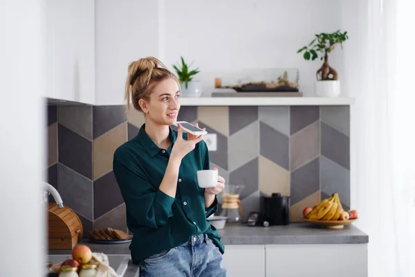 Retrato de estudiante joven con café en casa, usando smartphone. —  Fotos de Stock