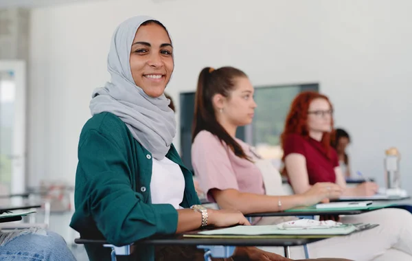 İslami üniversite öğrencisinin portresi, sınıfın içinde oturuyor, kameraya bakıyor.. — Stok fotoğraf