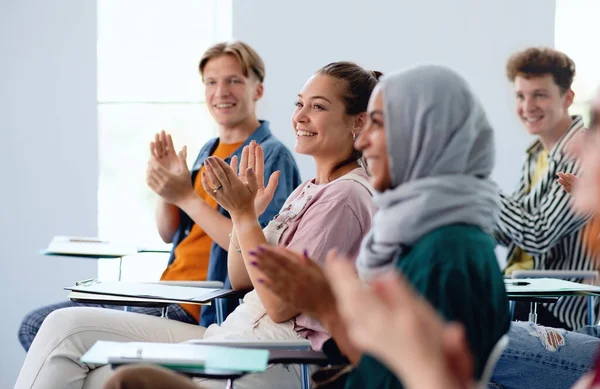 Porträtt av glada universitetsstuderande sitter och studerar i klassrummet inomhus, klappar. — Stockfoto