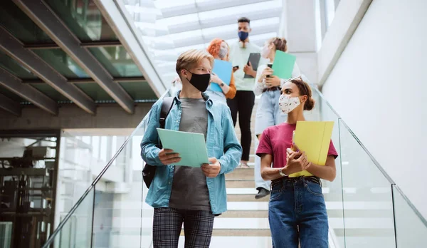 Estudantes universitários descendo as escadas e conversando dentro de casa, conceito coronavírus. — Fotografia de Stock