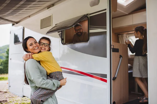 Mor kramar dotter med bil utomhus på campingen i skymningen, husvagn familjesemester resa. — Stockfoto