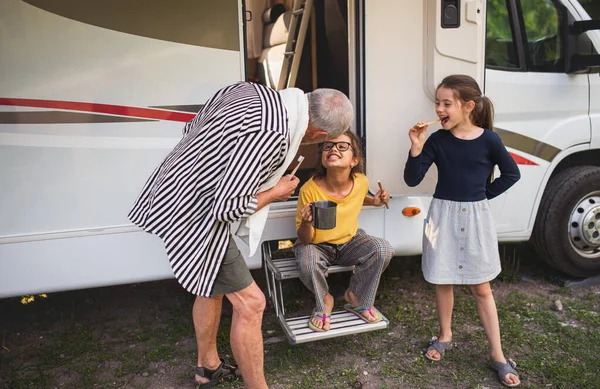 Glada små flickor med farfar borsta tänderna med husvagn, familjesemester resa. — Stockfoto
