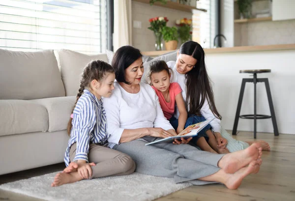Gelukkig kleine meisjes met moeder en grootmoeder binnen thuis, lezen verhaal boek. — Stockfoto