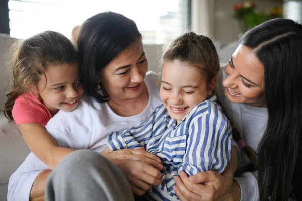 Happy small girls with mother and grandmother indoors at home, hugging. — Stock Photo, Image