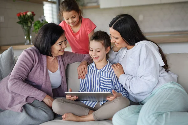 Happy kleine meisjes met moeder en grootmoeder binnen thuis, met behulp van tablet. — Stockfoto