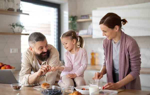 Family with small daughter indoors in kitchen at home, everyday life and home office with child concept. — Stock Photo, Image