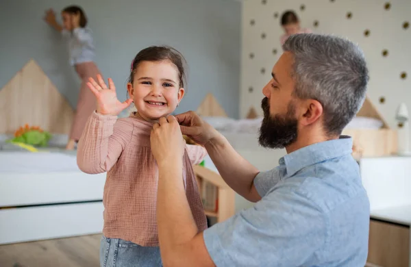 Vader met drie dochters binnen thuis, helpen om aan te kleden. — Stockfoto