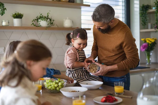 Father with three daughters indoors at home, eating breakfast in kitchen. — Stock Photo, Image