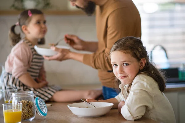 Father with daughters indoors at home, eating breakfast in kitchen. — Stock Photo, Image