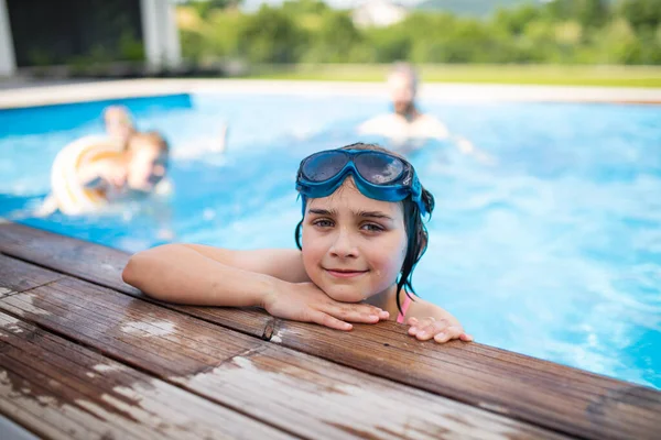 Niña pequeña con gafas al aire libre en el patio trasero, sentada en la piscina y mirando a la cámara. — Foto de Stock