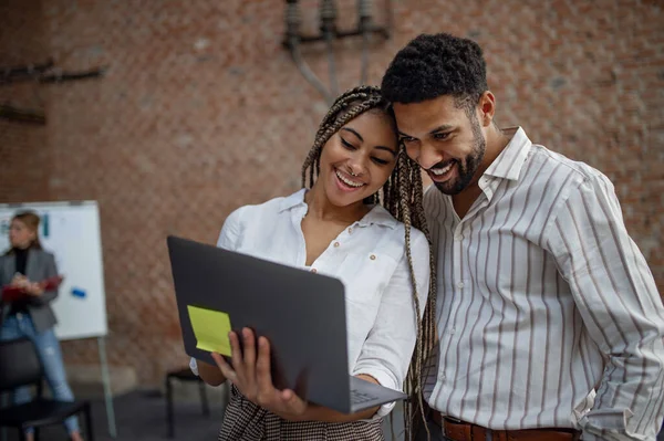 Fröhliche Jungunternehmer mit Laptop im Büro, Kooperationskonzept. — Stockfoto